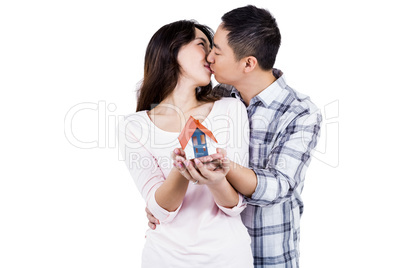 Couple kising while holding a model house