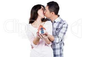 Couple kising while holding a model house