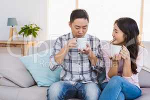 Happy woman looking at man while holding coffee cup