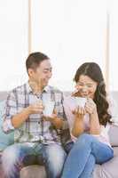Happy couple holding coffee cup while sitting on sofa