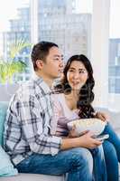 Happy woman looking at man while sitting on sofa