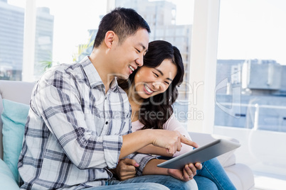 Young cheerful couple looking at digital tablet