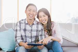 Young happy couple holding digital tablet