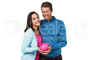 Smiling couple holding piggy bank