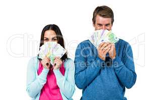 Portrait of couple hiding face with money