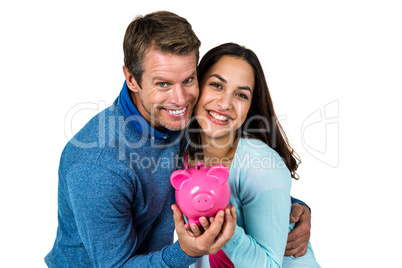 Smiling couple with pink piggy bank