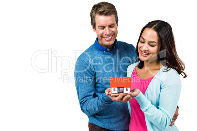 Smiling couple holding model house