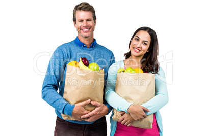Smiling man and woman holding bag of fruits