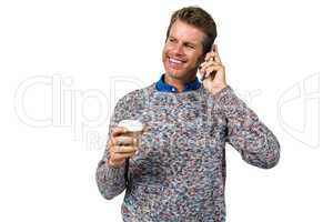 Smiling man holding coffee while talking on phone