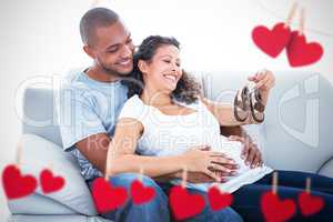 Composite image of couple with baby shoes