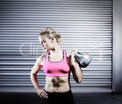 Composite image of muscular woman lifting heavy kettlebell