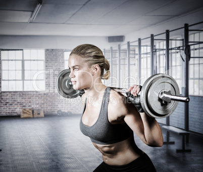 Composite image of muscular woman lifting heavy barbell