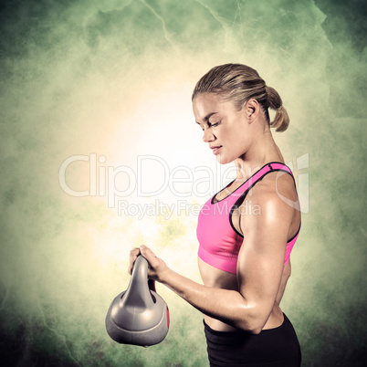 Composite image of muscular woman lifting heavy kettlebell