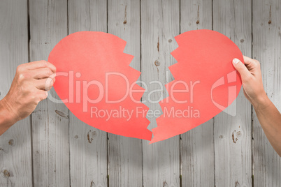 Composite image of cropped couple hands holding red cracked hear