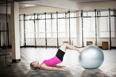 Composite image of side view of woman exercising with ball