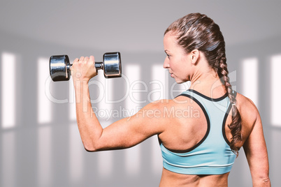 Composite image of rear view of woman lifting dumbbell