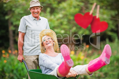 Composite image of happy senior couple playing with a wheelbarro