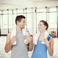 Composite image of happy fit young couple with water bottles