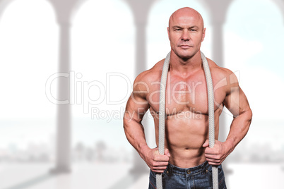 Composite image of portrait of healthy man holding rope