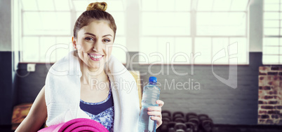 Composite image of fit brunette holding yoga mat