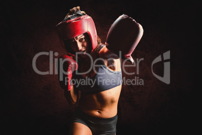 Composite image of female boxer with gloves and headgear punchin