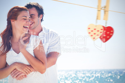 Composite image of happy couple hugging and laughing together