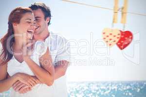 Composite image of happy couple hugging and laughing together