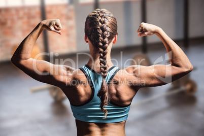 Composite image of rear view of woman with braided hair flexing