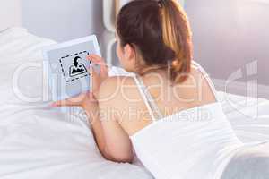 Composite image of relaxed woman using digital tablet in bed