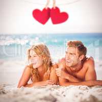 Composite image of happy couple relaxing together in the sand