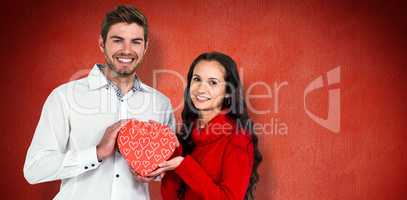 Composite image of couple holding heart shaped gift box