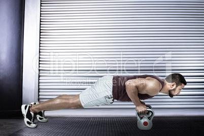 Composite image of muscular man doing push ups with kettlebells