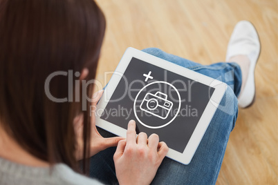 Composite image of girl using a tablet pc sitting on the floor