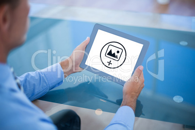 Composite image of businessman using his tablet