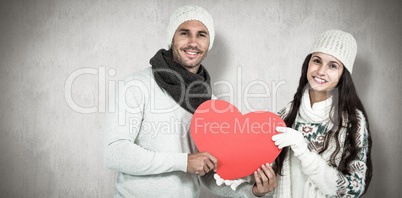 Composite image of smiling couple holding paper heart