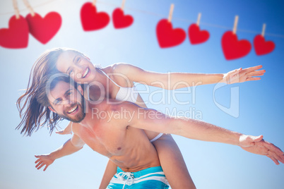 Composite image of handsome man giving piggy back to his girlfri