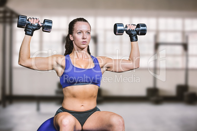 Composite image of confident woman lifting dumbbells