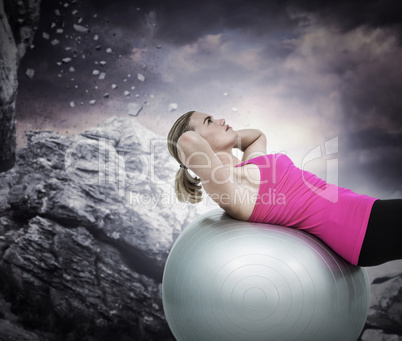 Composite image of muscular woman exercising on ball