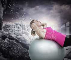 Composite image of muscular woman exercising on ball