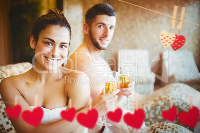 Composite image of happy couple celebrating with champagne