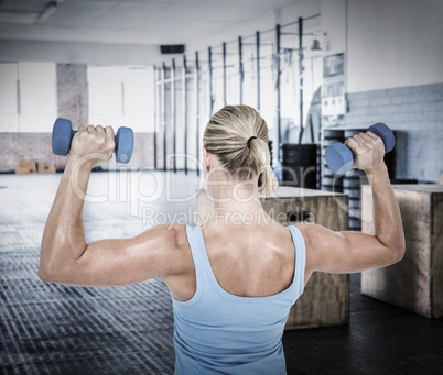 Composite image of muscular woman exercising with dumbbells