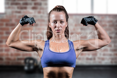 Composite image of portrait of woman with gloves flexing muscles