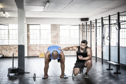 Composite image of man lifting barbell with trainer