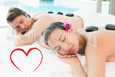 Composite image of couple enjoying stone massage at health farm