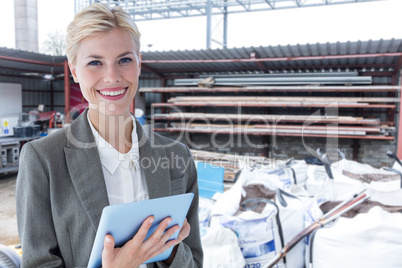 Composite image of smiling buisnesswoman using digital tablet