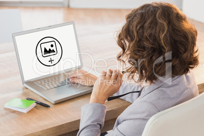 Composite image of businesswoman using laptop at desk in creativ