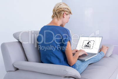 Composite image of blonde woman using her laptop on the couch