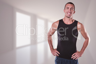 Composite image of happy athlete with hands on hip standing