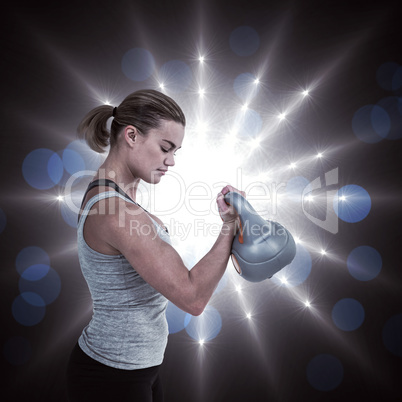 Composite image of serious muscular woman lifting kettlebell