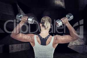 Composite image of  muscular woman working out with dumbbells